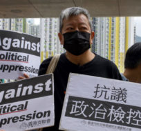 Pro-democracy activist Lee Cheuk-yan holds placards as he arrives at a court in Hong Kong this month. Vincent Yu/AP Photo
