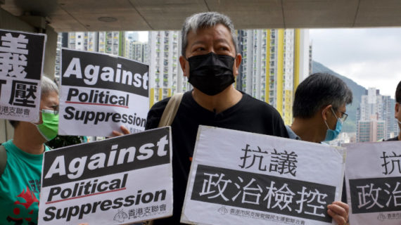 Pro-democracy activist Lee Cheuk-yan holds placards as he arrives at a court in Hong Kong this month. Vincent Yu/AP Photo