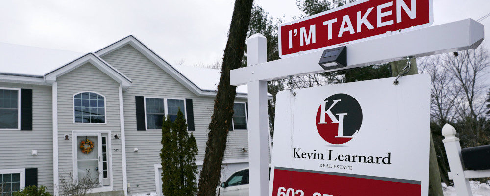 A placard rests on a real estate for sale sign outside a home. Charles Krupa/AP Photo