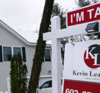 A placard rests on a real estate for sale sign outside a home. Charles Krupa/AP Photo