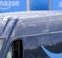 An Amazon Prime logo appears on the side of a delivery van as it departs an Amazon Warehouse. Steven Senne/AP Photo.