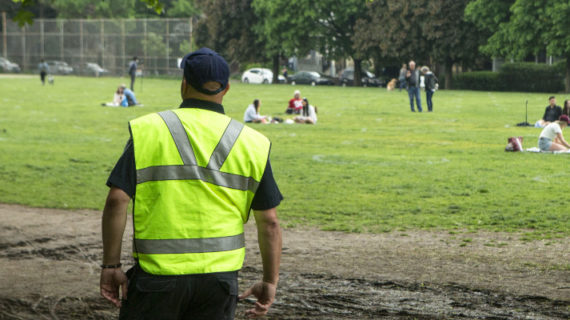 A city bylaw enforcer looks on as people sit within circles painted by the city in Toronto's Trinity Bellwoods Park. Chris Young/The Canadian Press.