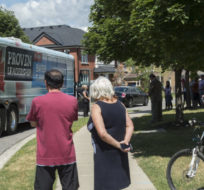 Local residents look at Conservative leader Stephen Harper's campaign bus as he makes a campaign stop at a suburban home in Richmond Hill, Ontario, on August 7, 2015. Paul Chiasson/The Canadian Press.