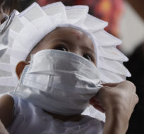 A woman adjusts the mask of her daughter to prevent spread of the coronavirus as they prepare for her baptism. Aaron Favila/AP Photo.