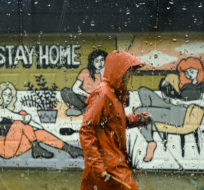 A person walks past a COVID-19 mural designed by artist Emily May Rose on a rainy day during the COVID-19 pandemic in Toronto on Monday, April 12, 2021. Nathan Denette/The Canadian Press.