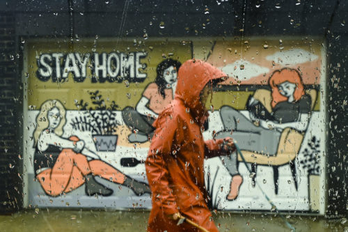 A person walks past a COVID-19 mural designed by artist Emily May Rose on a rainy day during the COVID-19 pandemic in Toronto on Monday, April 12, 2021. Nathan Denette/The Canadian Press.