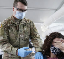 Leanne Montenegro, 21, covers her eyes as she doesn't like the sight of needles, while she receives the Pfizer COVID-19 vaccine at a FEMA vaccination center at Miami Dade College on April 5, 2021, in Miami. Lynne Sladky/AP Photo.