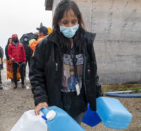 A lady carries water jugs on the Neskantaga First Nation, Ont., Monday, Sept. 13, 2021. Jonathan Hayward/The Canadian Press.