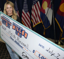 Heidi Russell of Aurora, Colo., takes the facsimile of her check after a news conference on July 7, 2021, to introduce her as the final $1-million winner in the state's vaccine lottery. David Zalubowski/AP Photo.