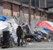 This Thursday, June 27, 2019, photo shows a man holding a bicycle tire outside of a tent along a street in San Francisco. Jeff Chiu, File/AP Photo.