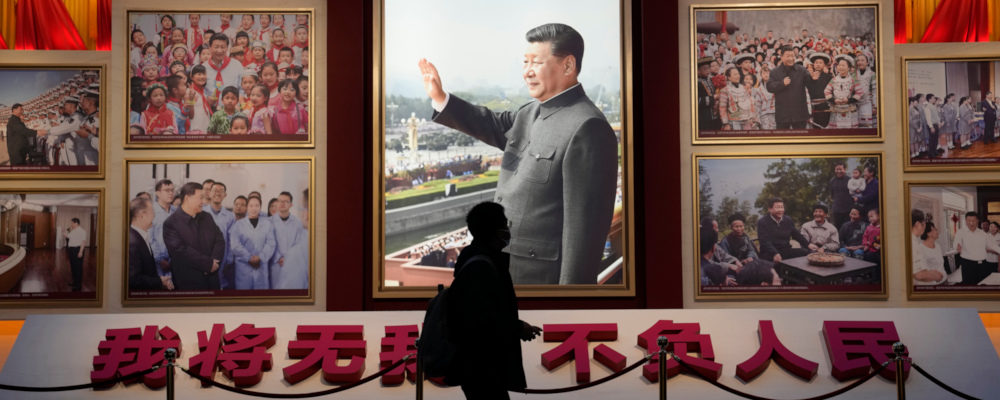 A visitor past by a photo of the Chinese President Xi Jinping and the slogan "I will have no self and live up to the People" at the Museum of the Communist Party of China in Beijing, China, Friday, Nov. 12, 2021. Ng Han Guan/AP Photo.