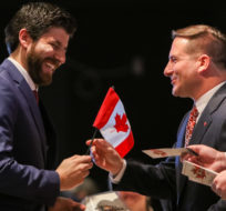 Tareq Hadhad receives a Canadian flag from Minister of Immigration, Refugees and Citizenship Marco Mendicino at the Oath of Citizenship ceremony at The Canadian Museum of Immigration at Pier 21 in Halifax on Wednesday, Jan. 15, 2020. Riley Smith/THE CANADIAN PRESS.