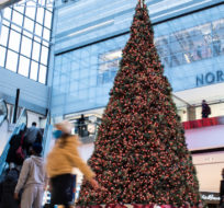 People pass a large Christmas tree as they go shopping on Christmas Eve at a mall in Ottawa, Thursday, Dec. 24, 2020. Justin Tang/The Canadian Press.
