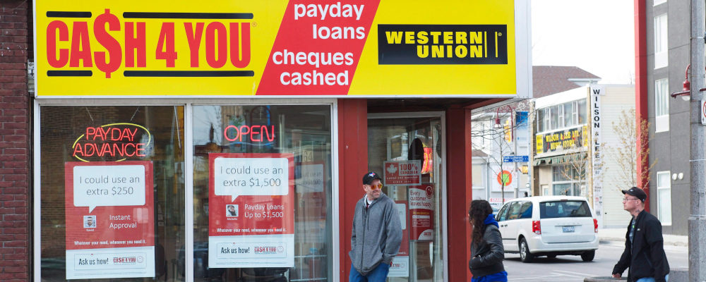 People walk pass a pay day loan store in Oshawa Ont. on Saturday May 13, 2017. Doug Ives/The Canadian Press. 
