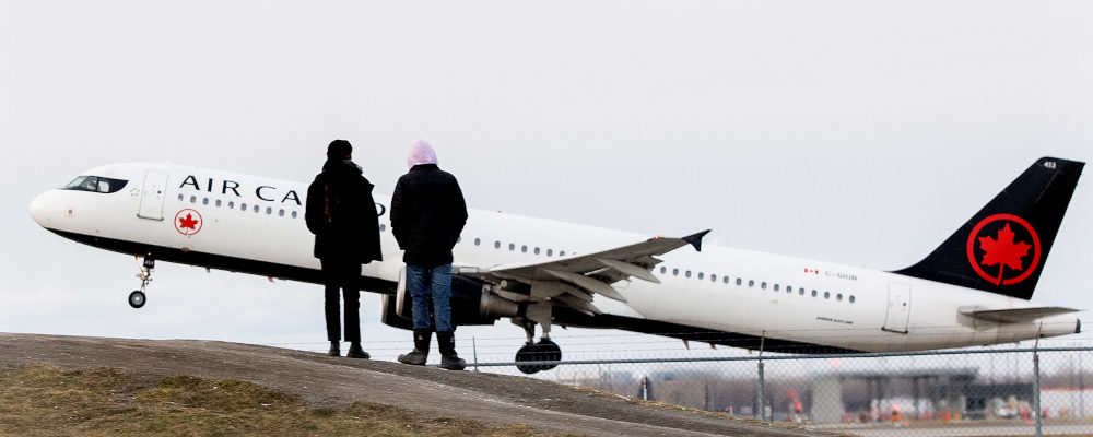 People look on as an Air Canada plane takes off from Montreal Trudeau Airport in Montreal, Sunday, December 5, 2021, as the COVID-19 pandemic continues in Canada and around the world. Graham Hughes/The Canadian Press.