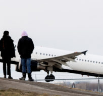 People look on as an Air Canada plane takes off from Montreal Trudeau Airport in Montreal, Sunday, December 5, 2021, as the COVID-19 pandemic continues in Canada and around the world. Graham Hughes/The Canadian Press.