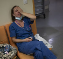 Nurse Marie-Laure Satta caresses her face during a pause in her New Year's Eve shift in the COVID-19 intensive care unit at the la Timone hospital in Marseille on Dec. 31, 2021. Daniel Cole/AP Photo.