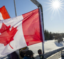 Supporters wave flags on an overpass in Kanata, Ont., as a trucker convoy making it's way to Parliament Hill in Ottawa. Frank Gunn/The Canadian Press.