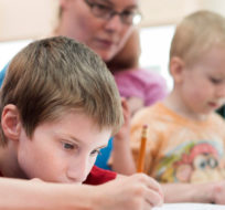 Tristan Fletcher, left, seven-years-old, works on math lessons with his mother Lisa Marie, and brothers Sebastian, 2, and William, 11, at the Whitby Central Library in Whitby, Ont. on Tuesday, August 11, 2015. Darren Calabrese/The Canadian Press.