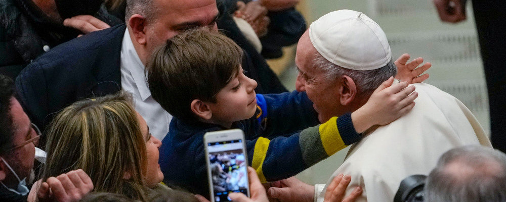 Pope Francis is hugged by a boy at the end of his weekly general audience in the Paul VI Hall at the Vatican, Wednesday, Dec. 15, 2021. Alessandra Tarantino/AP Photo.