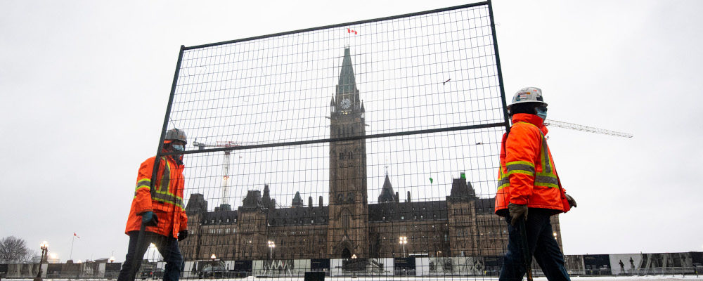 Crews carry a piece of fencing that will be used to shore up the existing gates along Wellington Street on Parliament Hill in Ottawa, on Thursday, Feb. 17, 2022. Justin Tang/The Canadian Press.
