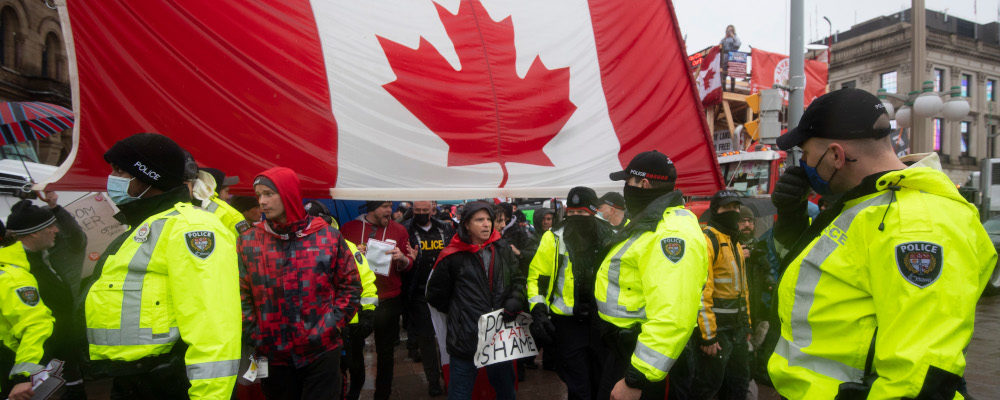 Police are followed by yelling protesters as they attempt to hand out a notices to protesters on the 21st day of a protest against COVID-19 measures that has grown into a broader anti-government protest, in Ottawa, on Thursday, Feb. 17, 2022. Justin Tang/The Canadian Press. 