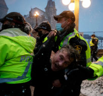 A man is arrested by police as protestors and supporters gather as a protest against COVID-19 measures that has grown into a broader anti-government protest continues to occupy downtown Ottawa on Thursday, Feb. 17, 2022. Cole Burston/The Canadian Press.