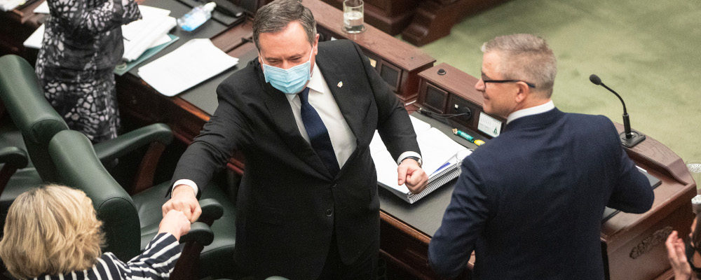 Alberta Premier Jason Kenney fist bumps an MLA after Finance Minister Travis Toews delivered the 2022 budget in Edmonton on Thursday February 24, 2022. Jason Franson/The Canadian Press. 