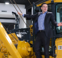 Pierre Poilievre climbs on a pipeline laying machine at a press conference at Brandt Tractor Ltd. in Regina on Friday, March 4, 2022. Michael Bell/The Canadian Press.