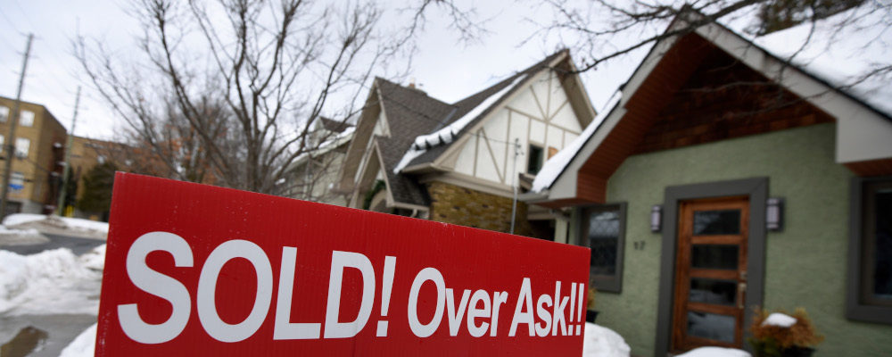 A for sale sign outside a home indicates that it has sold for over the asking price, in Ottawa, on Monday, March 1, 2021. Justin Tang/The Canadian Press.