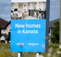 A sign in a field advertises new homes being built and for sale in a new subdivision in the Ottawa suburb of Kanata, on Friday, July 30, 2021. Justin Tang/The Canadian Press.
