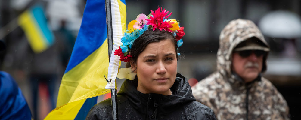 Melissa Funes Fedosenko wears flowers in her hair as she carries a Ukrainian flag during a rally in support of the people of Ukraine, in Vancouver, B.C., Sunday, April 3, 2022. Darryl Dyck/The Canadian Press.