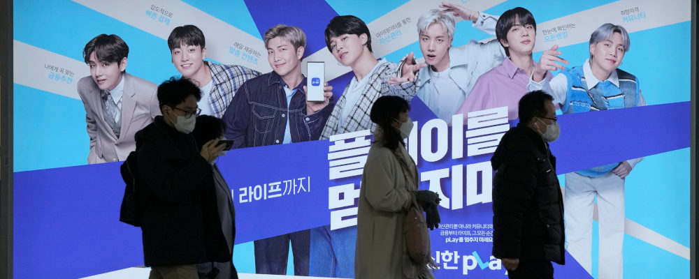People pass by an advertisement showing members of South Korean K-Pop group BTS promoting a local bank at a subway station in Seoul, South Korea, Friday, Dec. 17, 2021. Ahn Young-joon/AP Photo.