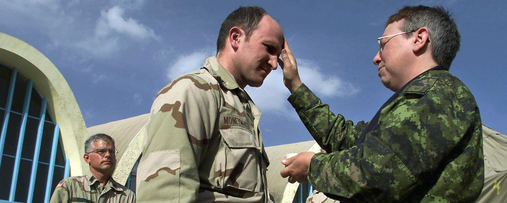 Canadian military chaplain Major Laurelle Callaghan of Edmonton  (right) makes the sign of the cross on the forehead of an American soldier during Ash Wednesday services at the airbase in Kandahar, Afghanistan Wednesday February 13, 2002. Kevin Frayer/CP Photo.