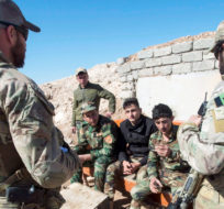 Canadian special forces soldiers, left and right, speak with Peshmerga fighters at an observation post, Monday, February 20, 2017 in northern Iraq. Ryan Remiorz/The Canadian Press.