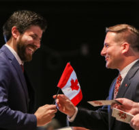 Tareq Hadhad receives a Canadian flag from Immigration Minister Marco Mendicino at the Oath of Citizenship ceremony at The Canadian Museum of Immigration at Pier 21 in Halifax on Jan. 15, 2020. Riley Smith/The Canadian Press.