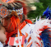 David White holds his friend, two-year-old Kova Macey as he waits to dance in a First Nations Pow-Wow, at the Canada Day celebration, Monday July 1, 2013 London, Ontario. Dave Chidley/The Canadian Press.