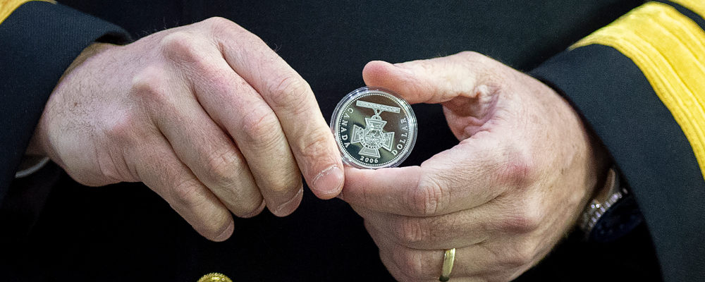 Rear Admiral Brian Santarpia holds  a Canadian one dollar coin marking the 150th Anniversary of the Victoria Cross in 2006 at the keel laying ceremony of the future HMCS HMCS William Hall at Irving Shipbuilding in Halifax on Wednesday, Feb. 17, 2021. Andrew Vaughan/The Canadian Press.