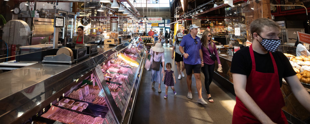 People walk past a butcher shop at the Granville Island Market in Vancouver, on July 20, 2022. Darryl Dyck/The Canadian Press.