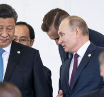 Russian President Vladimir Putin, top right, and China's President Xi Jinping, top left, talk to each other as they and other leaders walk to attend the BRICS emerging economies at the Itamaraty palace in Brasilia, Brazil, Thursday, Nov. 14, 2019. Pavel Golovkin/AP Photo.