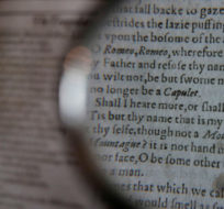 Looking through a magnifying glass to read lines from the play 'Romeo and Juliet' as William Shakespeare's First Folio is displayed at Christie's auction rooms in London, Monday, Jan. 13, 2020. The book was published in 1623 and contains 36 of Shakespeare's plays. The book which will go for auction in New York on April 24, is estimated at 4-6 million US dollars. Kirsty Wigglesworth/AP Photo.