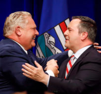 Ontario Premier Doug Ford, left, and United Conservative Leader Jason Kenney embrace on stage at an anti-carbon tax rally in Calgary, Friday, Oct. 5, 2018. Jeff McIntosh/The Canadian Press. 