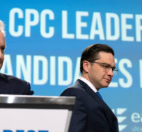 Conservative leadership candidate Pierre Poilievre, right, walks past Jean Charest as he takes his place on stage during a debate at the Canada Strong and Free Network conference, in Ottawa, Thursday, May 5, 2022. Adrian Wyld/The Canadian Press.
