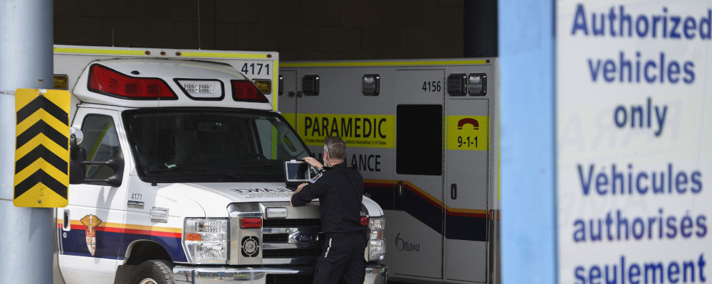A paramedic works on a laptop on the hood of an ambulance in Ottawa on May 16, 2022. Justin Tang/The Canadian Press.