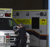 A paramedic works on a laptop on the hood of an ambulance in Ottawa on May 16, 2022. Justin Tang/The Canadian Press.