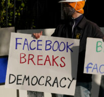 FILE - In this Saturday, Nov. 21, 2020, file photo, a demonstrator joins others outside of the home of Facebook CEO Mark Zuckerberg to protest what they say is Facebook spreading disinformation in San Francisco. Jeff Chiu/AP Photo.