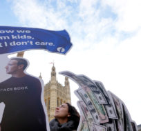 Senior campaigner from SumOfUs Flora Rebello Arduini adjusts an installation outside parliament in Westminster in London, Monday, Oct. 25, 2021. A 4-metre-high installation depicting Mark Zuckerberg surfing on a wave of cash was constructed outside parliament, as Facebook whistleblower Frances Haugen is due to testify to MPs on how the company puts profits ahead of public safety. The action comes after SumOfUs research revealed Instagram is still awash with posts promoting eating disorders, unproven diet supplements and skin-whitening products. Kirsty Wigglesworth/AP Photo.