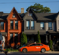 A person walks by a row of houses in Toronto on Tuesday July 12, 2022. Cole Burston/The Canadian Press.