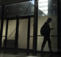 A man walks through a downtown Toronto office building with other buildings reflected in a window in this June 11, 2019 photo. Graeme Roy/The Canadian Press.