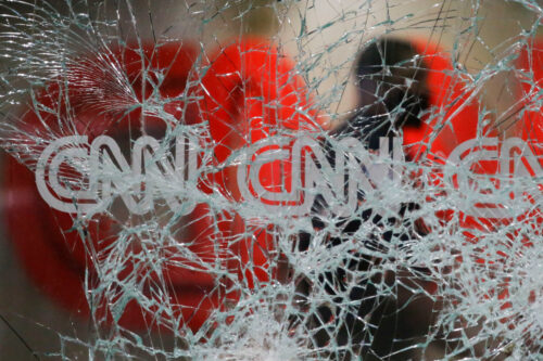 A security guard walks behind shattered glass at the CNN building at the CNN Center in the aftermath of a demonstration against police violence on Saturday, May 30, 2020, in Atlanta. Brynn Anderson/AP Photo.